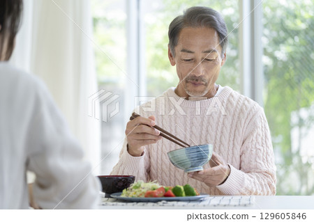 一名 60 多歲的男子正在吃飯 129605846
