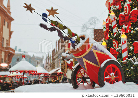 Winter Christmas decoration cannon with salute on city square in snow next to Christmas tree Winter Christmas decoration cannon with salute on city square in snow next to Christmas tree 129606031