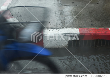 red and white curb road with drain hole in the rainy day red and white curb road with drain hole in the rainy day 129606339