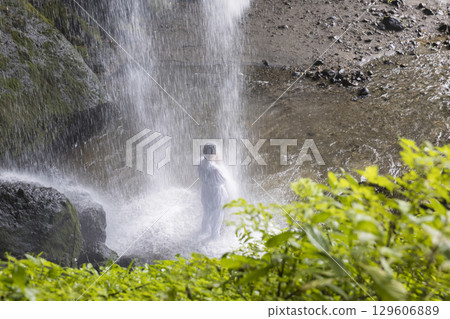 一位身穿白色長袍的女子正在進行瀑布訓練 129606889
