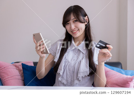 Smiling Japanese woman enjoying online shopping with her smartphone 129607194