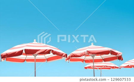 A row of red and white striped umbrellas on a sunny beach, ideal for summer vacations and enjoying the outdoors A row of red and white striped umbrellas on a sunny beach, ideal for summer vacations and enjoying the outdoors 129607533