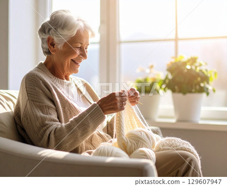 Elderly woman knitting by the window 129607947