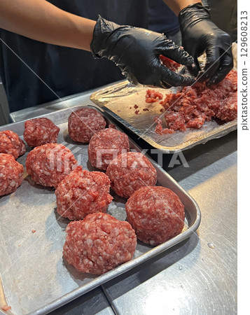 Cropped shot of a chef kneading beef meatballs to prepare hamburger cutlets in the kitchen of an American burger restaurant 129608213