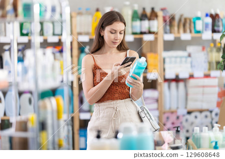 Girl client choose and scanning QR code on package shampoo or shower gel Girl client choose and scanning QR code on package shampoo or shower gel 129608648