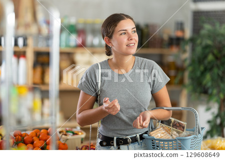 Woman in gray t-shirt in supermarket Woman in gray t-shirt in supermarket 129608649