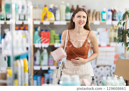 Woman with period pain choosing sanitary pads in store Woman with period pain choosing sanitary pads in store 129608661