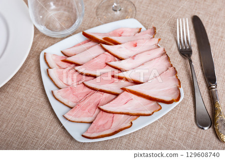 Plate is filled with slices of smoked meat fore shank. Plate is filled with slices of smoked meat fore shank. 129608740