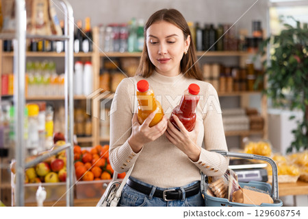 Young woman choosing juices in grocery store 129608754
