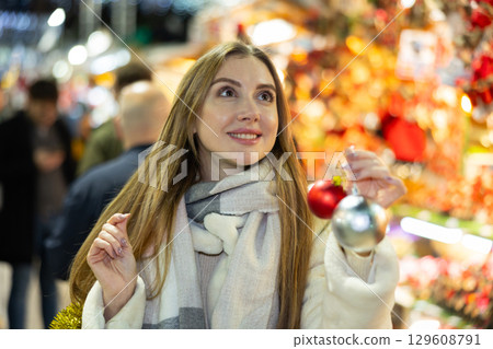 Young woman has purchased decorations for Christmas tree, tinsel and colorful balls Young woman has purchased decorations for Christmas tree, tinsel and colorful balls 129608791