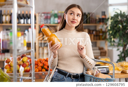 Young woman choosing peach juice in grocery store 129608795
