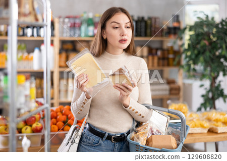 Young woman choosing cheese in grocery store 129608820