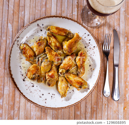 On plate is hearty snack - portion of fried chicken wings with crispy crust, poured with thick barbecue sauce On plate is hearty snack - portion of fried chicken wings with crispy crust, poured with thick barbecue sauce 129608895
