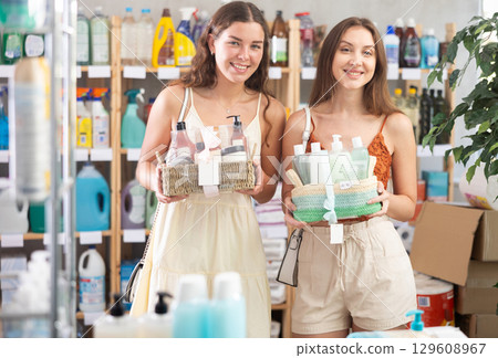 Cheerful female friends choosing gift set with self-care products in store 129608967