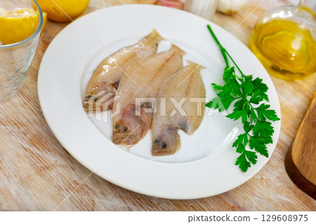 Raw scaldfish on plate with condiments prepared for cooking 129608975