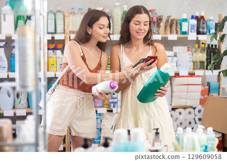 Women friends scanning qr code for detergent Women friends scanning qr code for detergent 129609058