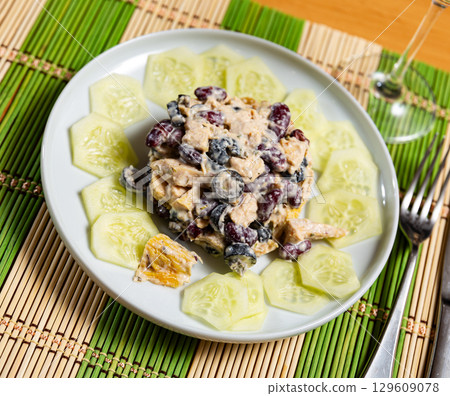 Pyramid of salad from olives, chicken, beans, decorated with slices of cucumber along edge of plate Pyramid of salad from olives, chicken, beans, decorated with slices of cucumber along edge of plate 129609078