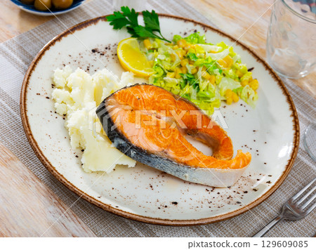 Salmon served with potatoes and salad 129609085
