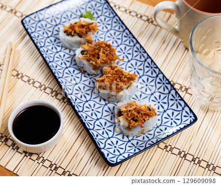 Plate is filled with crunch California rolls with fried puffed rice 129609098
