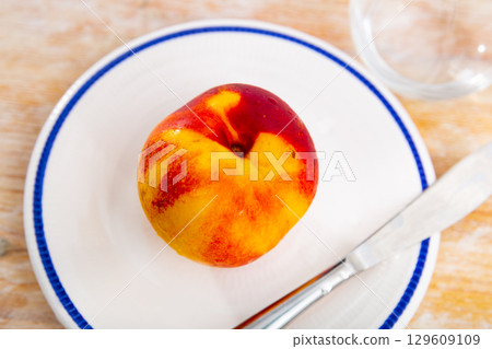 Ripe tasty nectarine on plate with knife. Tasty still life Ripe tasty nectarine on plate with knife. Tasty still life 129609109