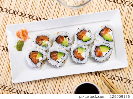Japanese Uramaki and California rolls served in a plate with soya sauce 129609126