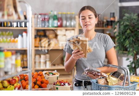 Grocery shopping at supermarket - girl chooses sweets, nougat, cookies and candies Grocery shopping at supermarket - girl chooses sweets, nougat, cookies and candies 129609129