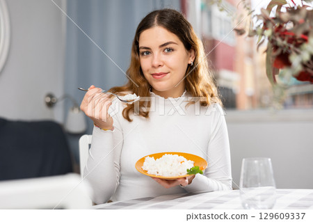 Positive woman eating portion of boiled rice at home 129609337
