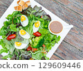 Boiled eggs with vegetables on wooden table. Salad for diet food 129609446