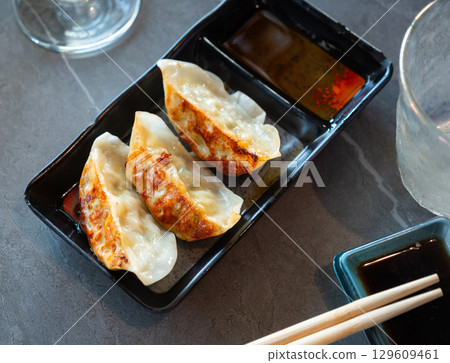 Image of Japanese tasty dumplings gyozas with soy sauce served on black plate 129609461