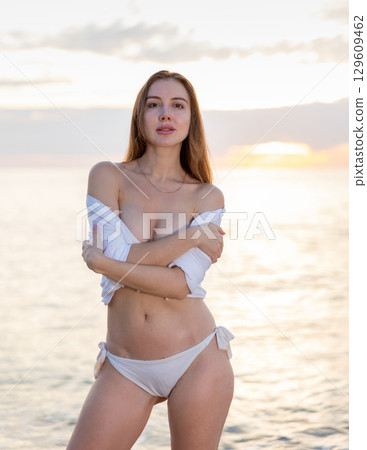 Woman with athletic body on a tropical beach wearing white bikini 129609462