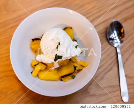 Grilled pineapple slices complemented with vanilla ice cream Grilled pineapple slices complemented with vanilla ice cream 129609531