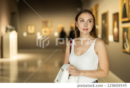 Girl view pictures and icons in museum hall 129609545