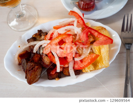 Fried pork is laid out on plate, with fried cassava and salad - Latin American tapita dish. 129609564