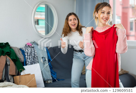 Two young women choosing clothes to wear Two young women choosing clothes to wear 129609581