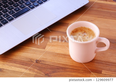 Image of a man working on his laptop while drinking freshly brewed delicious coffee Image of a man working on his laptop while drinking freshly brewed delicious coffee 129609977