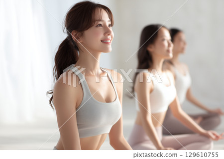 Woman doing yoga in a bright studio, healthy lifestyle 129610755