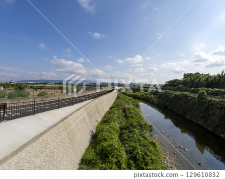 A view of the Senri River bank with a paved embankment road 129610832