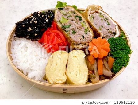 A colorful dosirak lunchbox filled with neatly arranged rice, savory protein, and assorted side dishes. A portable feast that captures the essence of authentic Korean home-style cooking. 129612120