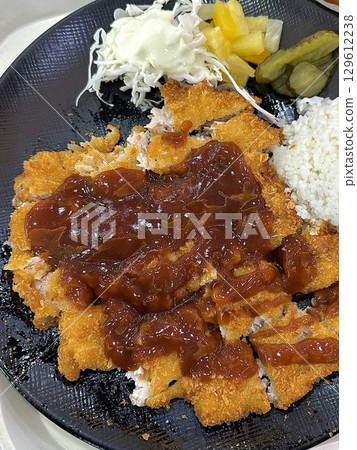 Crispy tonkatsu, a Japanese-style breaded and deep-fried pork cutlet, served with shredded cabbage and drizzled with savory sauce. A delightful balance of crunchy texture and juicy meat. Crispy tonkatsu, a Japanese-style breaded and deep-fried pork cutlet, served with shredded cabbage and drizzled with savory sauce. A delightful balance of crunchy texture and juicy meat. 129612238