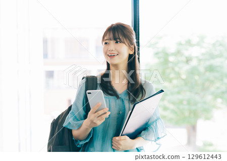 Female college student looking at a smartphone Female college student looking at a smartphone 129612443