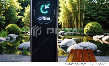 Green offline symbol glows on modern charging station display in peaceful garden setting, featuring lush bamboo, rocks, and pond, creating a serene atmosphere 129612724