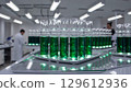 Bubbling green liquid filling test tubes during scientific research, laboratory professionals collaborating in background workspace, highlighting biotechnology investigation 129612936