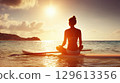 Woman Meditating on Paddleboard at Sunset Over Calm Tropical Ocean Waters 129613356