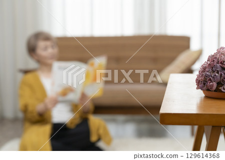 客廳沙發上看書的老年婦女 129614368