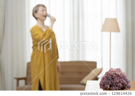 老年婦女在客廳沙發上唱卡拉 OK 作為愛好 129614426