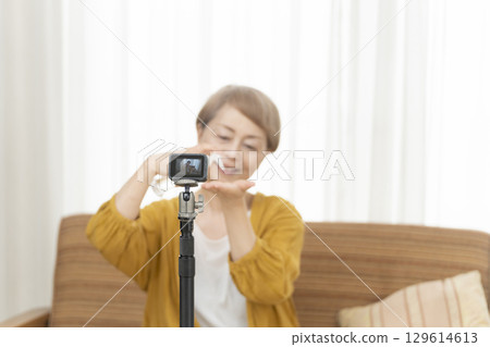 Senior woman streaming video in the living room 129614613