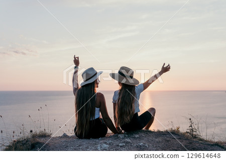 Two Women in Hats Enjoying Sunset Over the Sea Two Women in Hats Enjoying Sunset Over the Sea 129614648