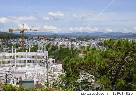 Aerial view of new building construction in city surrounded by forests with mountains on the horizon 129614920