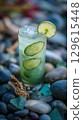 Refreshing Cucumber Lime Drink with Ice on Coastal Pebbles. 129615448
