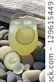 Refreshing Cucumber Lime Drink on a Pebble Beach with Driftwood. 129615449